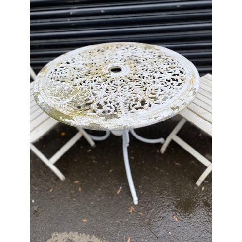 359 - White metal garden table with two white foldable chairs.