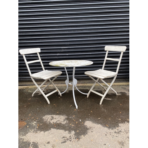 359 - White metal garden table with two white foldable chairs.