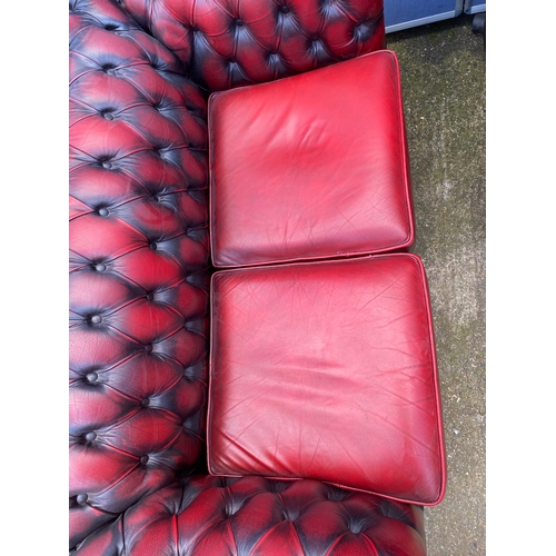 202 - Two crimson leather chesterfield sofas.