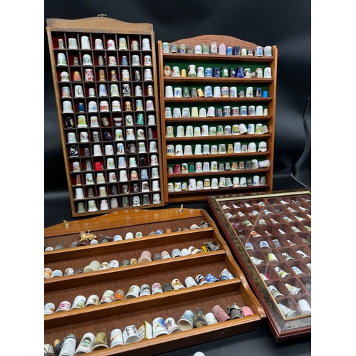 88 - Large quantity of decorative display thimbles including sterling silver thimbles on display cabinets