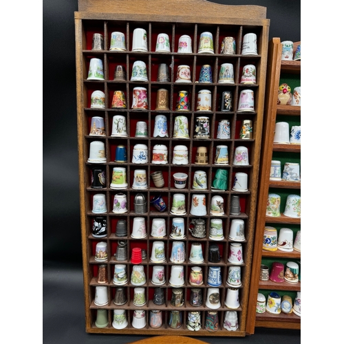 88 - Large quantity of decorative display thimbles including sterling silver thimbles on display cabinets