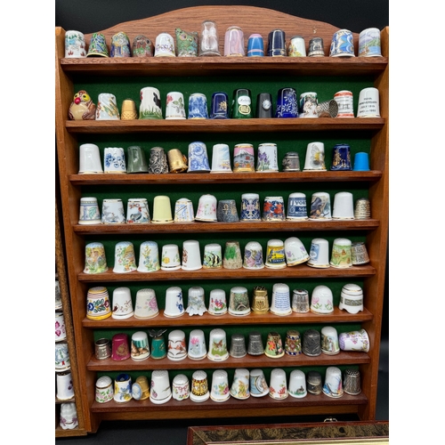 88 - Large quantity of decorative display thimbles including sterling silver thimbles on display cabinets