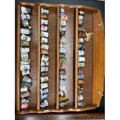 88 - Large quantity of decorative display thimbles including sterling silver thimbles on display cabinets