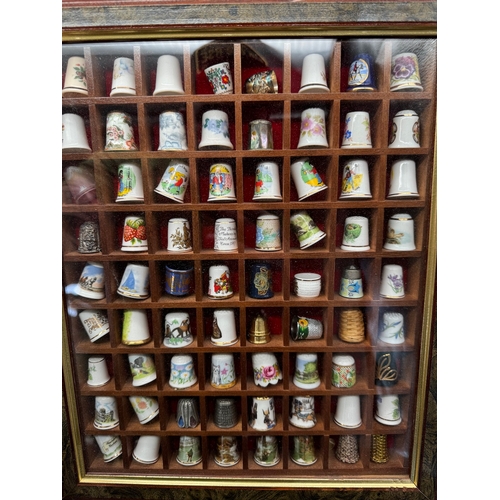 88 - Large quantity of decorative display thimbles including sterling silver thimbles on display cabinets