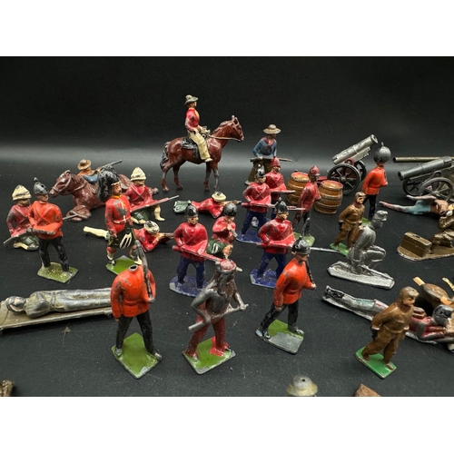 253 - A collection of early 20th century lead toy soldiers, cowboys + military badges