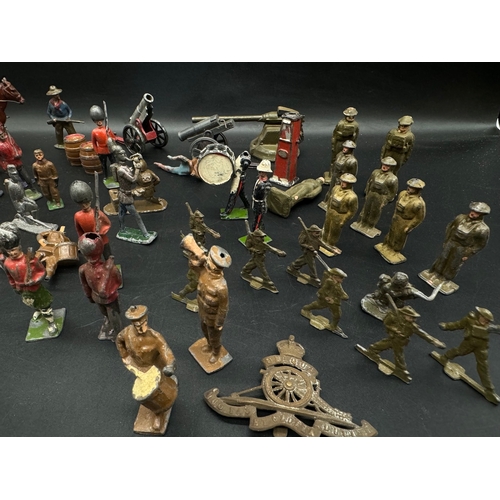 253 - A collection of early 20th century lead toy soldiers, cowboys + military badges