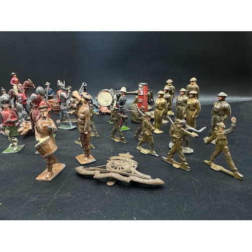 253 - A collection of early 20th century lead toy soldiers, cowboys + military badges