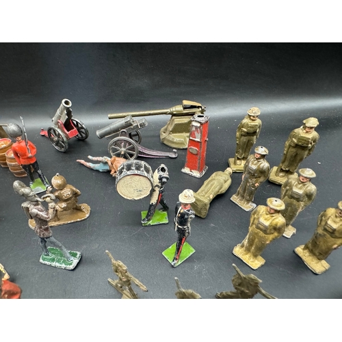 253 - A collection of early 20th century lead toy soldiers, cowboys + military badges