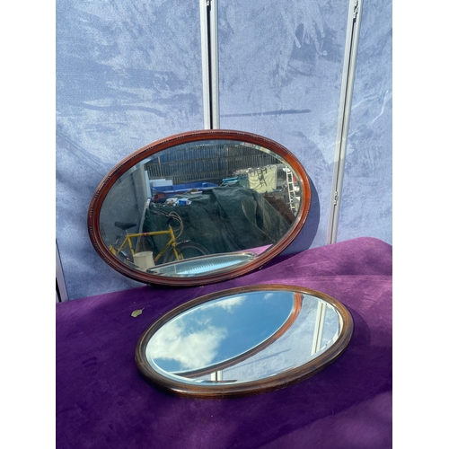 686 - Two oval wooden framed mirrors.