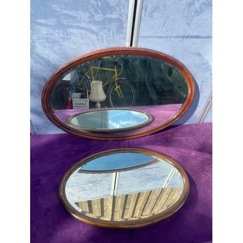 686 - Two oval wooden framed mirrors.