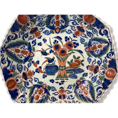 99 - A Polychrome tin-glazed Delft ware plate / dish. painted with vases of flowers and birds. Marked to ... 