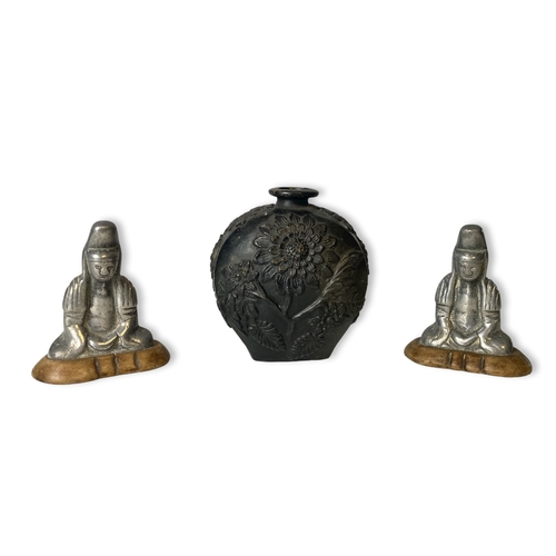 68C - A pair of metal Buddha figures on wooden base. Together with a relief decorated black pottery vase. ... 