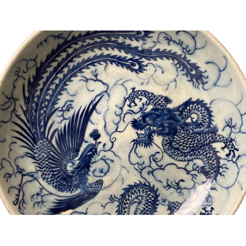 146 - A Chinese porcelain dish. Hand painted with a Dragon and Phoenix. Qing dynasty. 
27.5cm Diameter