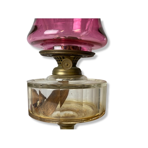 198 - A Victorian Cast iron & Brass Oil lamp, with Ruby glass shade. 
54cm Tall