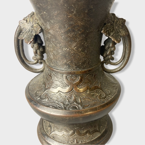 169 - A twin handle Chinese Qing dynasty Bronze vase.
Stylised grape vine handles. 
15cm tall