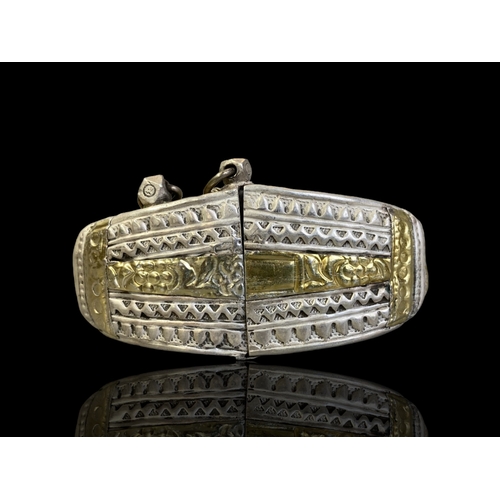 46 - OMANI TRIBAL SILVER & GOLD LEAF ANKLET.
1ST-HALF 20TH CENTURY.
STYLISED CHASED DESIGNS WITH APPLIED ... 