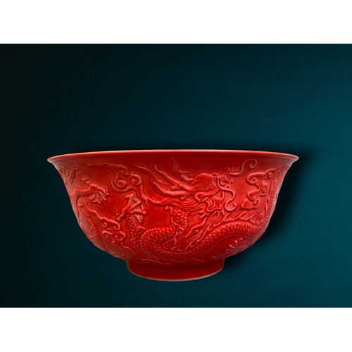 162 - A CHINESE RED GROUND PORCELAIN BOWL. RELIEF DECORATED WITH 5-CLAW DRAGON AMONGST THE CLOUDS. 
QIANLO... 