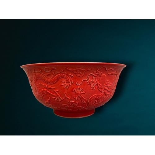 162 - A CHINESE RED GROUND PORCELAIN BOWL. RELIEF DECORATED WITH 5-CLAW DRAGON AMONGST THE CLOUDS. 
QIANLO... 