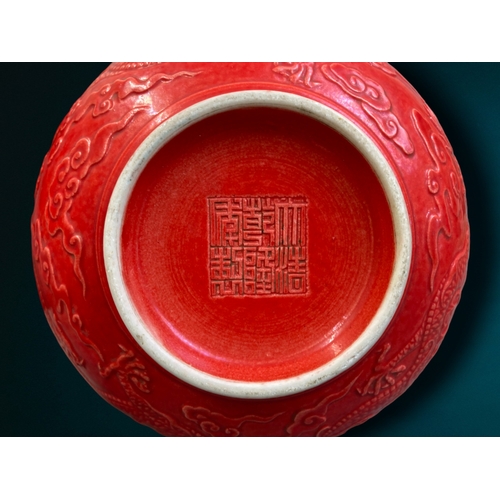 162 - A CHINESE RED GROUND PORCELAIN BOWL. RELIEF DECORATED WITH 5-CLAW DRAGON AMONGST THE CLOUDS. 
QIANLO... 