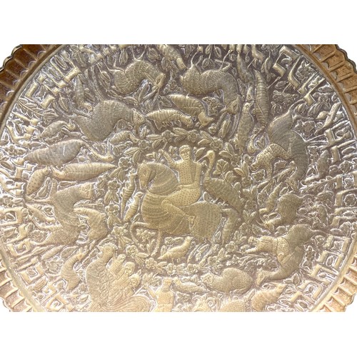 14 - large Persian Brass & wooden tray table.
Embossed brass tray depicting rider on horseback, surrounde... 