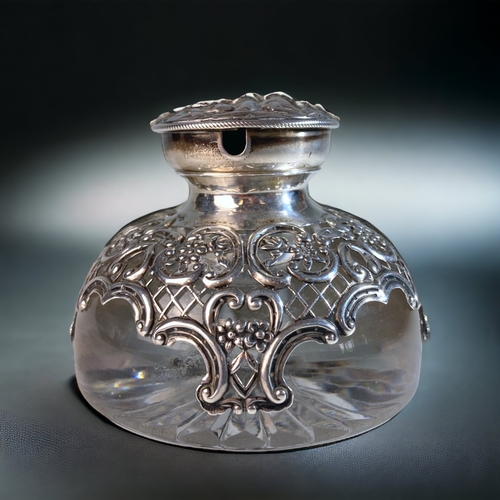 25 - AN EDWARDIAN WILLIAM COMYNS  & SONS REPOUSSÉ SILVER & CRYSTAL INKWELL, WITH WATCH HOLDER TO LID. 
LO... 