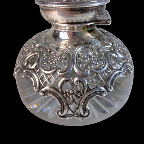 25 - AN EDWARDIAN WILLIAM COMYNS  & SONS REPOUSSÉ SILVER & CRYSTAL INKWELL, WITH WATCH HOLDER TO LID. 
LO... 