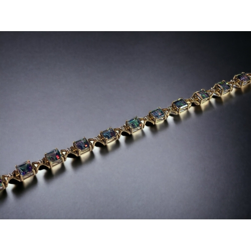 48 - A LADIES 9CT GOLD & MYSTIC TOPAZ LINE BRACELET. 
21CM LONG