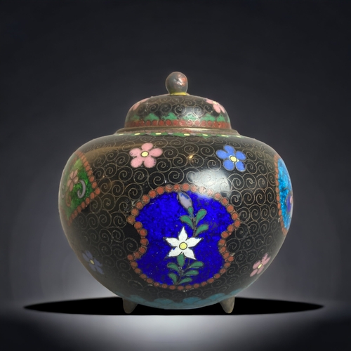 241 - A CHINESE CLOISONNE TRI-FOOTED CLOISONNE VASE & COVER. BLACK GROUND WITH COLOURFUL ENAMEL CARTOUCHE ... 