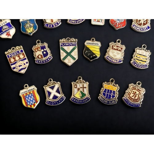 145 - A COLLECTION OF 24 SILVER & ENAMEL SOUVENIR CHARMS.