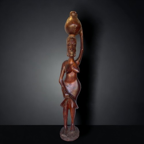 35 - A LARGE AFRICAN WOOD CARVING OF A WOMAN CARRYING A BOT. (38