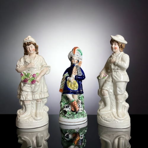 317 - A LARGE PAIR OF 19TH CENTURY STAFFORDSHIRE 'FLOWER SELLERS' FIGURES. TOGETHER WITH A HIGHLANDER. 
TA... 