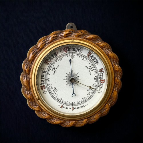 253 - AN EDWARDIAN OAK ROPE FORM ANEROID BAROMETER WITH PORCELAIN DIAL.
19CM DIAMETER