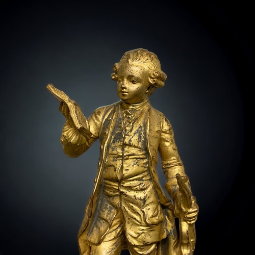 239 - A GILT BRONZE FIGURE OF A YOUNG MOZART. AFTER EMILE BRUCHON. ON MARBLE BASE. 325.CM TALL.