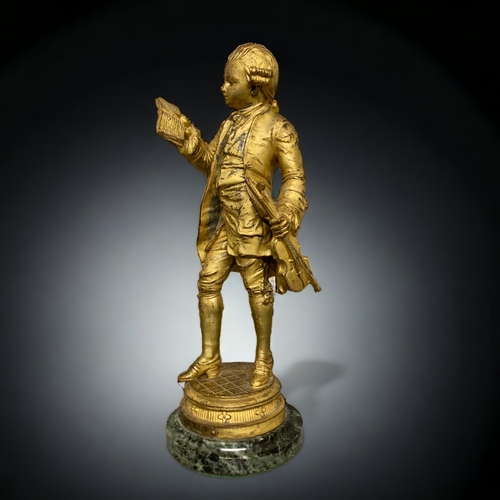 239 - A GILT BRONZE FIGURE OF A YOUNG MOZART. AFTER EMILE BRUCHON. ON MARBLE BASE. 325.CM TALL.