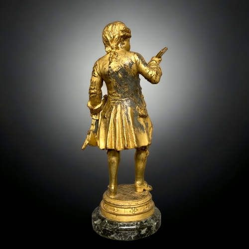 239 - A GILT BRONZE FIGURE OF A YOUNG MOZART. AFTER EMILE BRUCHON. ON MARBLE BASE. 325.CM TALL.