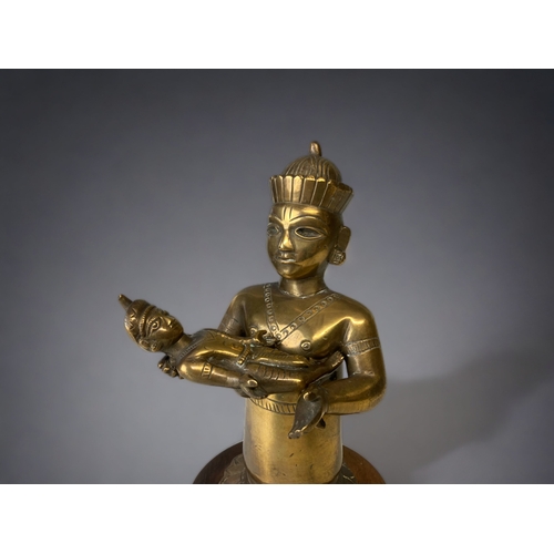 12 - A 19TH CENTURY SOUTH ASIAN BRONZE DEITY DEITY HOLDING A (DETACHABLE) BABY ALOFT. MOUNTED ON RAISED W... 