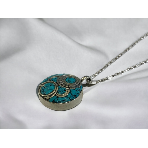 176 - A TIBETAN TURQUOISE SILVER INLAID PENDANT ON STERLING SILVER CHAIN.