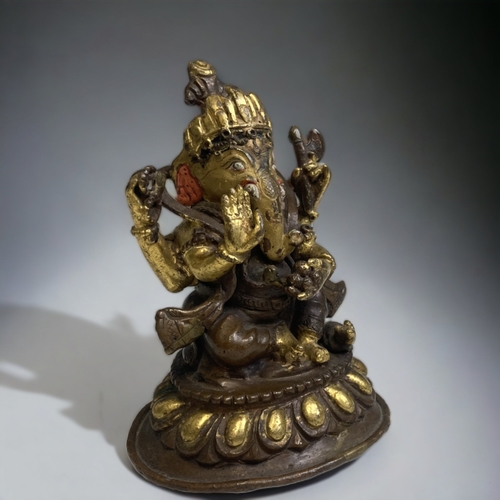 306 - AN INDIAN PATINATED & GILT BRONZE FIGURE OF GANESH. 
HEIGHT - 10CM