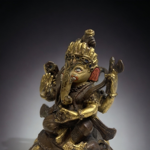 306 - AN INDIAN PATINATED & GILT BRONZE FIGURE OF GANESH. 
HEIGHT - 10CM