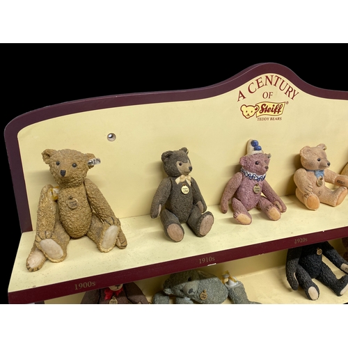 525 - A COLLECTION OF NINE 'A CENTURY OF STEIFF' PORCELAIN TEDDY BEARS. WITH COLLECTORS DISPLAY SHELF.