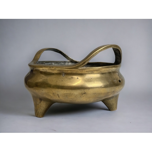 70 - A large Chinese polished bronze twin handle censer. 
Qing dynasty.  Raised on three tapered feet.
Re... 