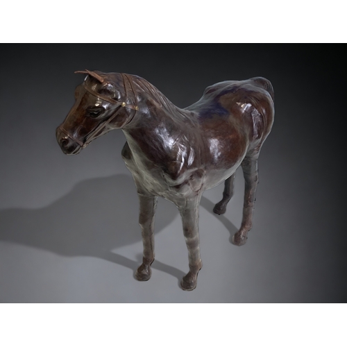 726 - In the manner of Liberty & Co, a stuffed leather Horse. 
With glass eyes. 
Height - 47 cm