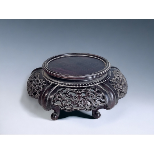 177 - A CHINESE CARVED WOOD STAND.
Raised on four curved feet. With stylised foliate design.