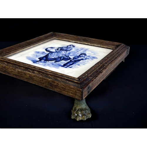 133 - A PAINTED DELFT TILE TRIVET STAND.
19th Century. 
Wood framed, with gilt metal Lion paw feet. 
5 x 2... 