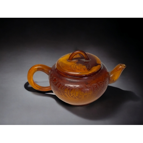 68 - A CHINESE CARVED AMBER TEAPOT.
Qing dynasty. 
Carved Tokens with script to body and lid. 
Impressed ... 