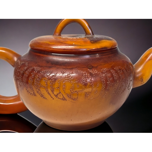 68 - A CHINESE CARVED AMBER TEAPOT.
Qing dynasty. 
Carved Tokens with script to body and lid. 
Impressed ... 