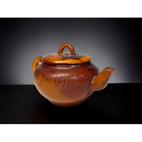 68 - A CHINESE CARVED AMBER TEAPOT.
Qing dynasty. 
Carved Tokens with script to body and lid. 
Impressed ... 