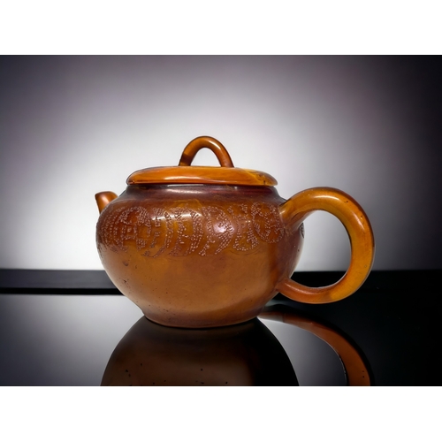 68 - A CHINESE CARVED AMBER TEAPOT.
Qing dynasty. 
Carved Tokens with script to body and lid. 
Impressed ... 