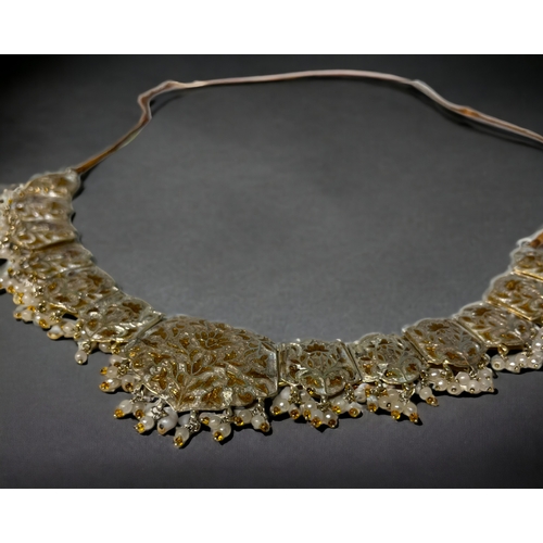 394 - A PERSIAN? WHITE & GILT METAL ENAMELLED CHOKER NECKLACE.
Stylised foliate design, with drop pearls &... 