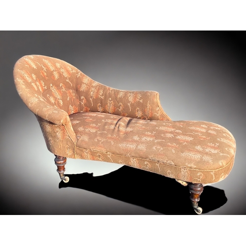 251 - A Victorian Mahogany frame Chaise lounge.
Original patterned upholstery, with turned Mahogany legs a... 